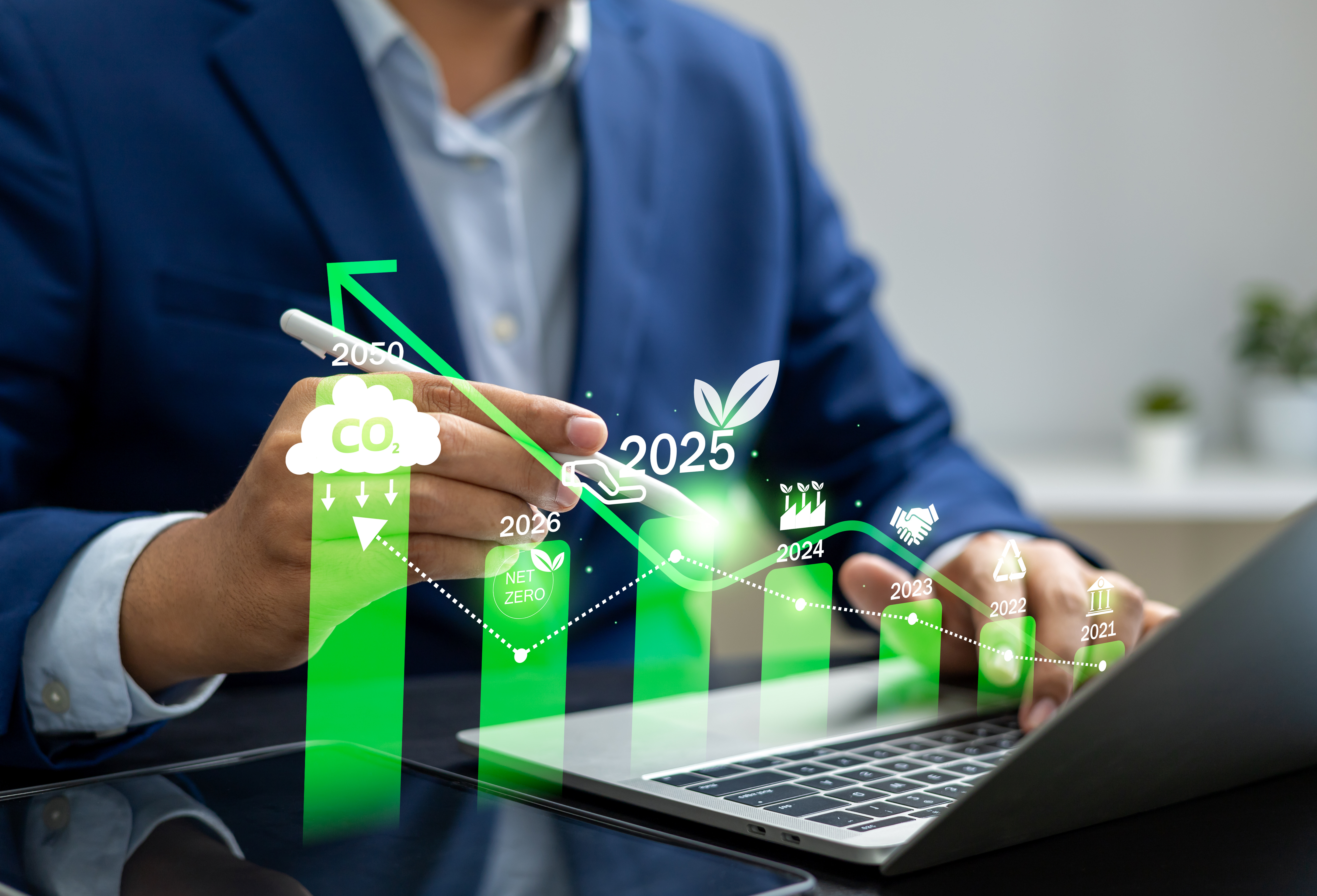 Business professional analyzing a carbon emission reduction graph showing CO2 decline and energy goals for 2025, symbolizing Optimum Energy’s commitment to net-zero and sustainable operations.